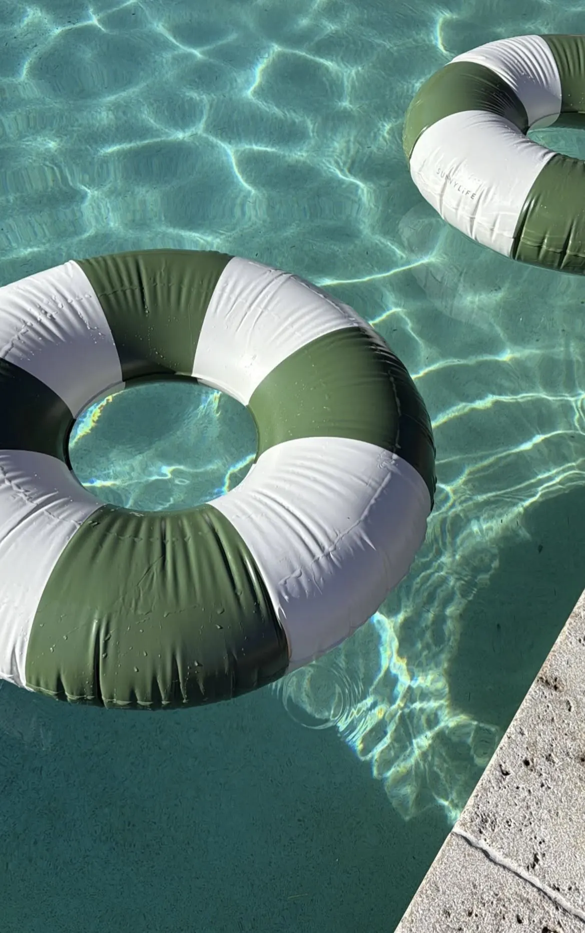 Olive and white striped inflatable rings on clear water